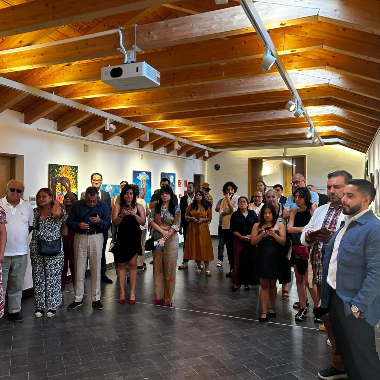 Público en inauguración · Sala con vigas de madera
