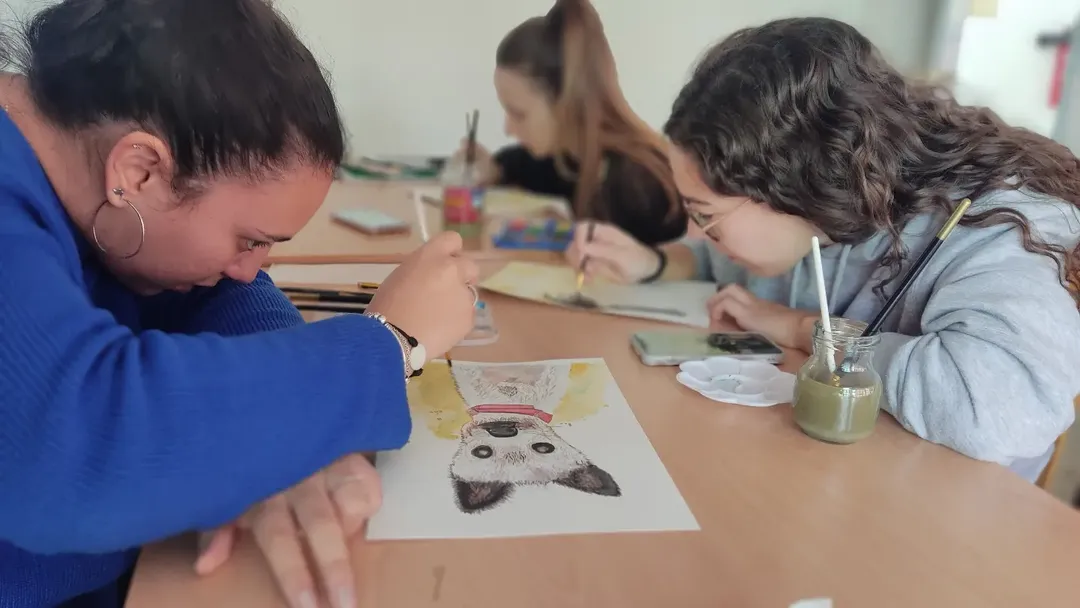 Jóvenes pintando con acuarela el retrato de un animal durante una sesión del taller